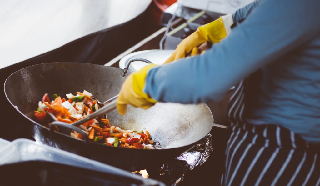 a chef cooking in a big wok outside